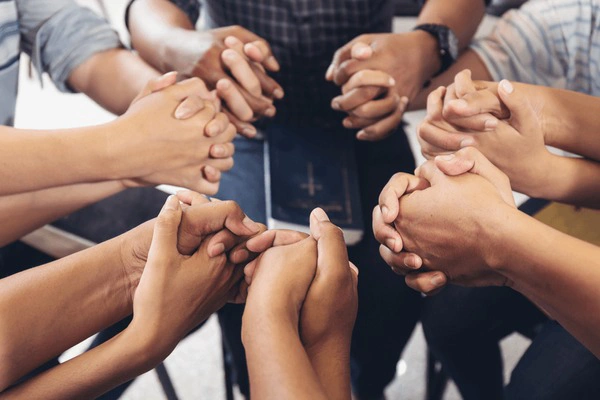 A group of people holding hands in a circle, symbolizing unity and community.